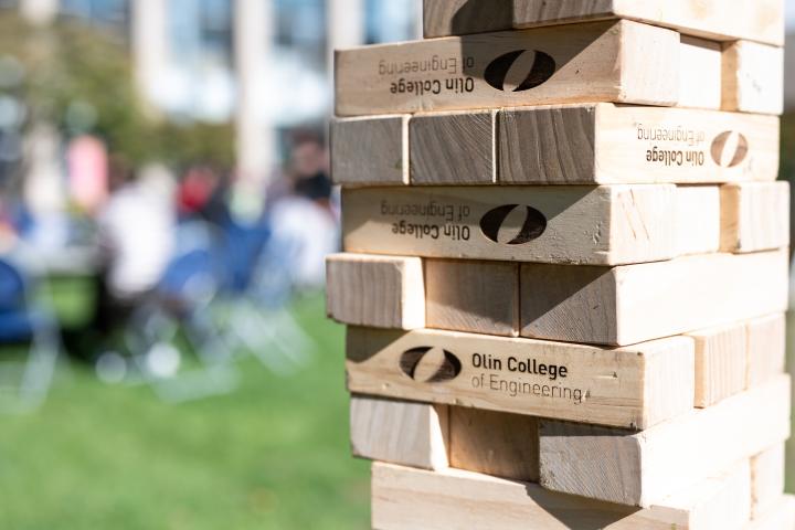 A tower of Jenga blocks with the Olin College of Engineering logo and branding emblazoned on the wood. 