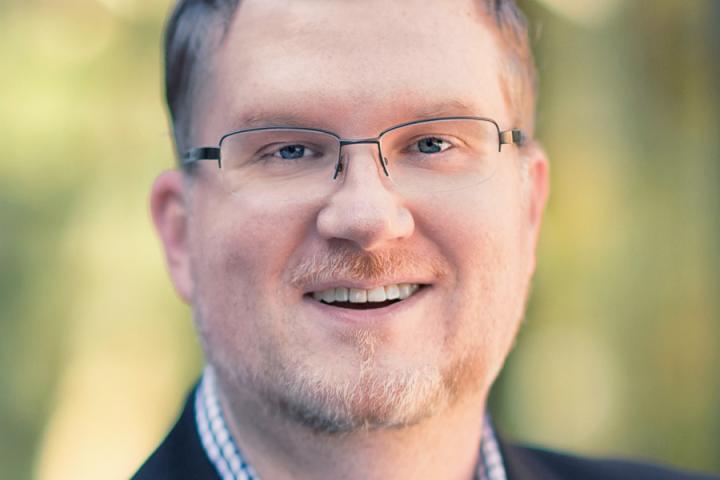 Portrait of Jacob Graham'06 smiling, light brown hair, glasses