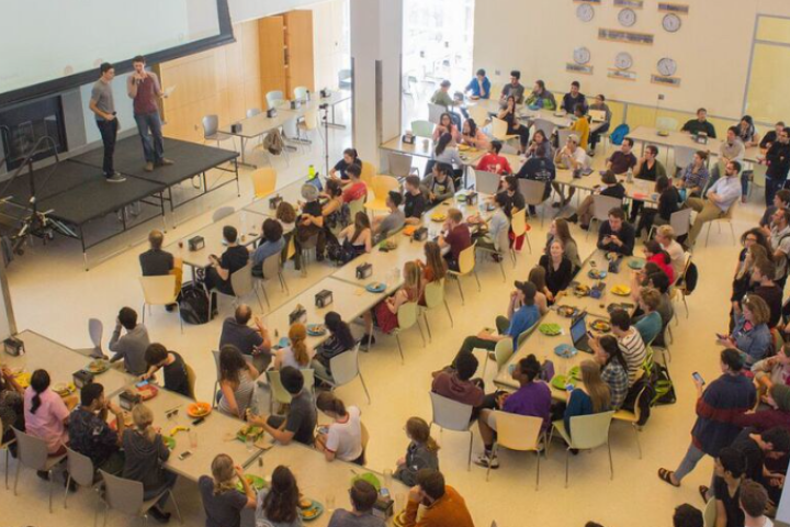2017 SERV Auction overhead view of dining hall full of students watching two people on stage