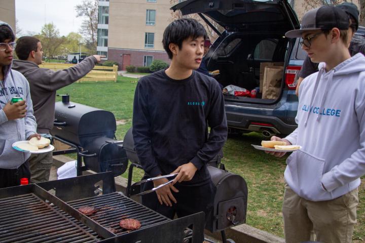 Students stand next to an outdoor grill during BOW SLACFEST in April 2023.