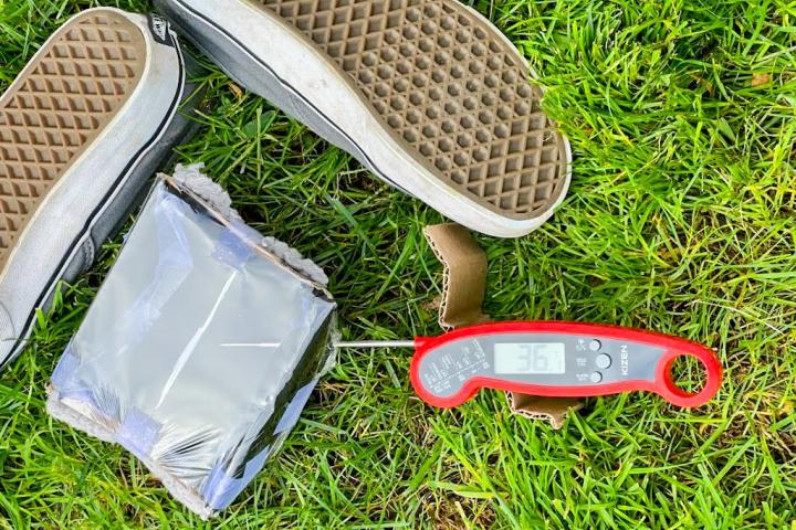 An image of a pair of shoes, a grey-taped box and a red thermometer that reads 36.1 degrees 