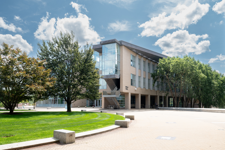 A photo of a campus building with a blue sky and puffy clouds as the backdrop