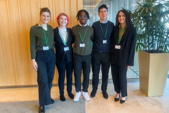 Five students with name badges in corporate lobby