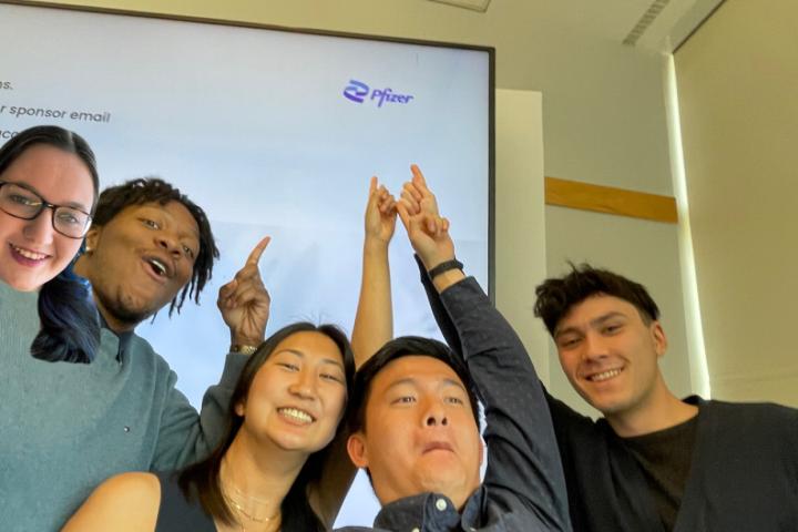 Pfizer SCOPE Team 2024 Five students taking a selfie and pointing at Pfizer logo