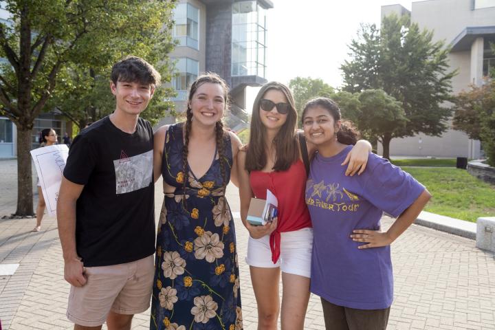 four students standing outdoors with arms around each other