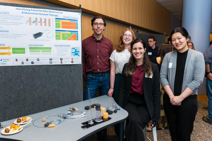 Students posing in front of project poster at Summit
