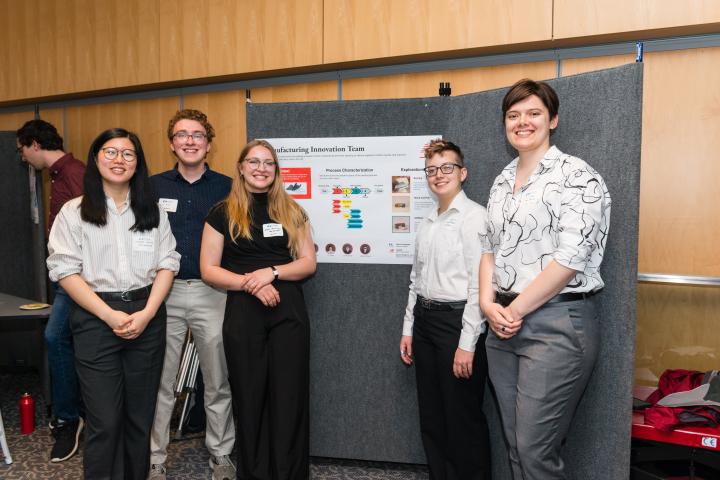 Students posing in front of project poster at Summit