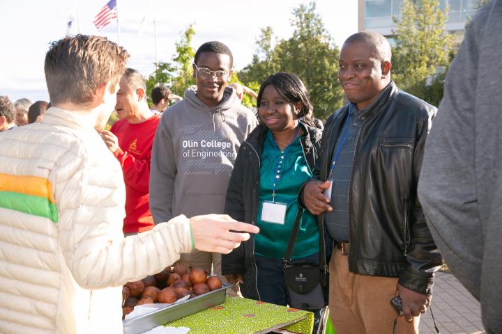 A family of two parents and a son is pictured at a college event in the fall. 