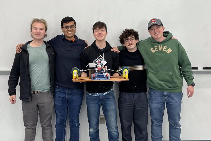 Five Olin College of Engineering students hold up a physical, electromechanical Turing Machine.