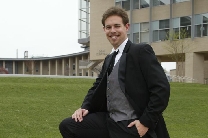 Kevin Tostado ’06 poses beside Milas Hall. 