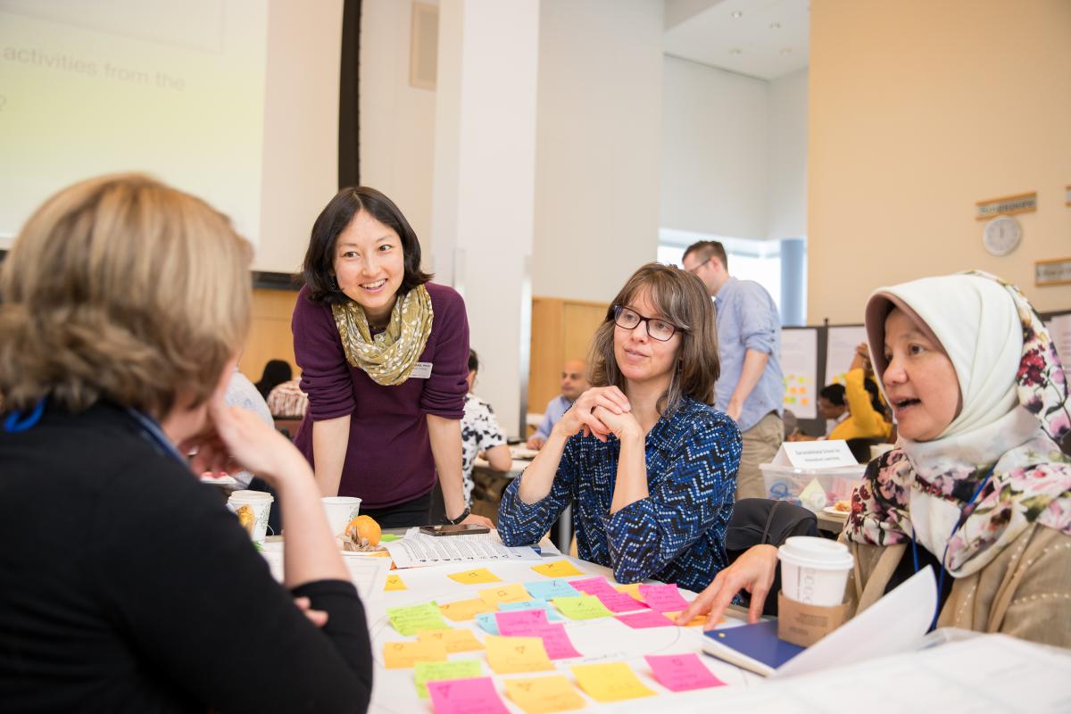 A photo of four educators sitting around a table with sticky notes in front of them