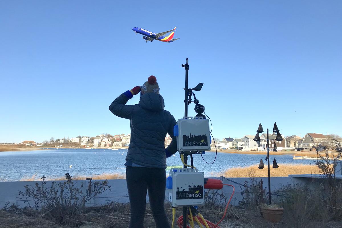 A photo of a person looking out over the water at an airplane in East Boston