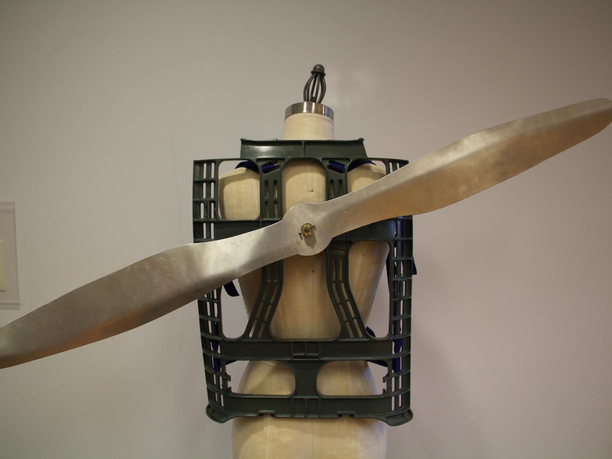 A gold and silver designed aluminum propeller attached to a black harness.