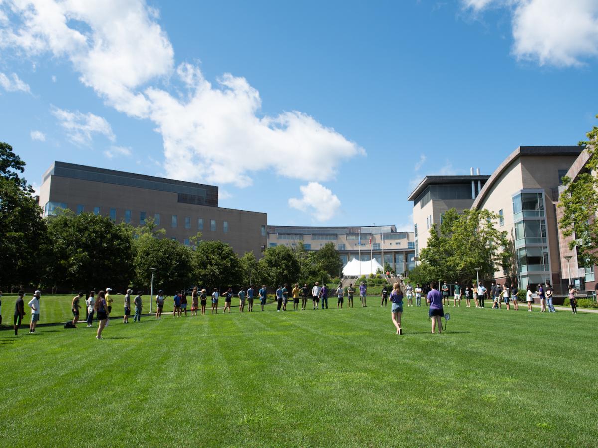 Olin College Orientation 2021 activities on the Great Lawn. Students form a half circle on the Great Lawn, under a blue sky, during Orientation 2021.