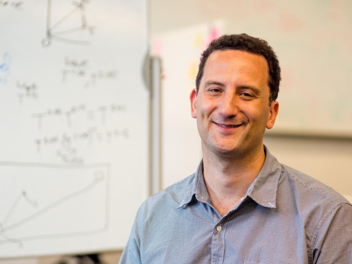 Paul Ruvolo, Associate Professor of Computer Science, in blueish grey shirt, smiles for a photo.