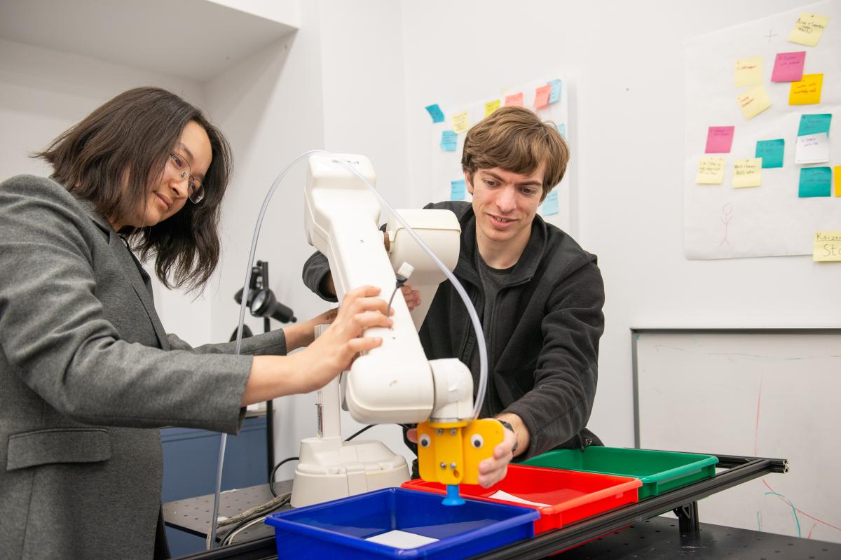 A photo of two people working on a robotic arm
