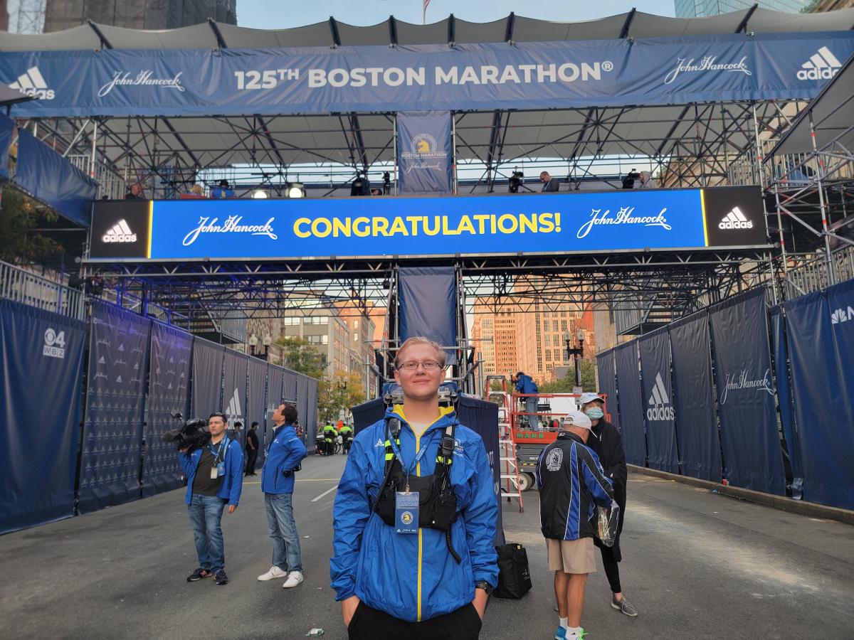 Olin student Phillip Post '25, in blue jacket, poses at the Boston Marathon finish line