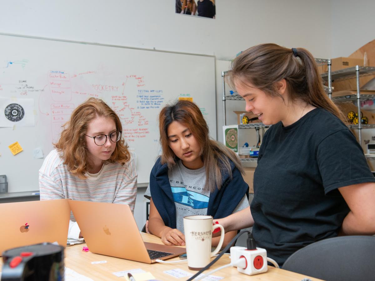 Three student researchers, including Berwin Lan '24 in the center, work on the tech platform project.