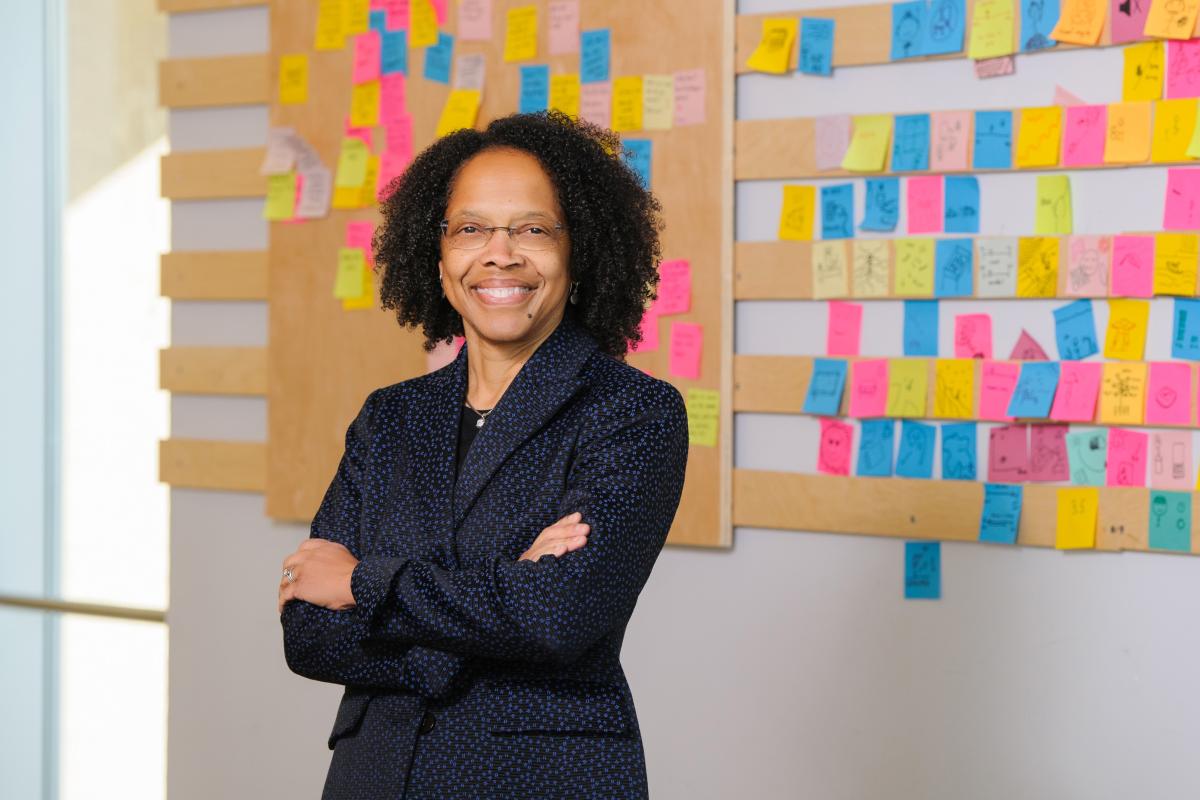 President Gilda A. Barabino stands in front of a wall with colorful sticky notes on it.