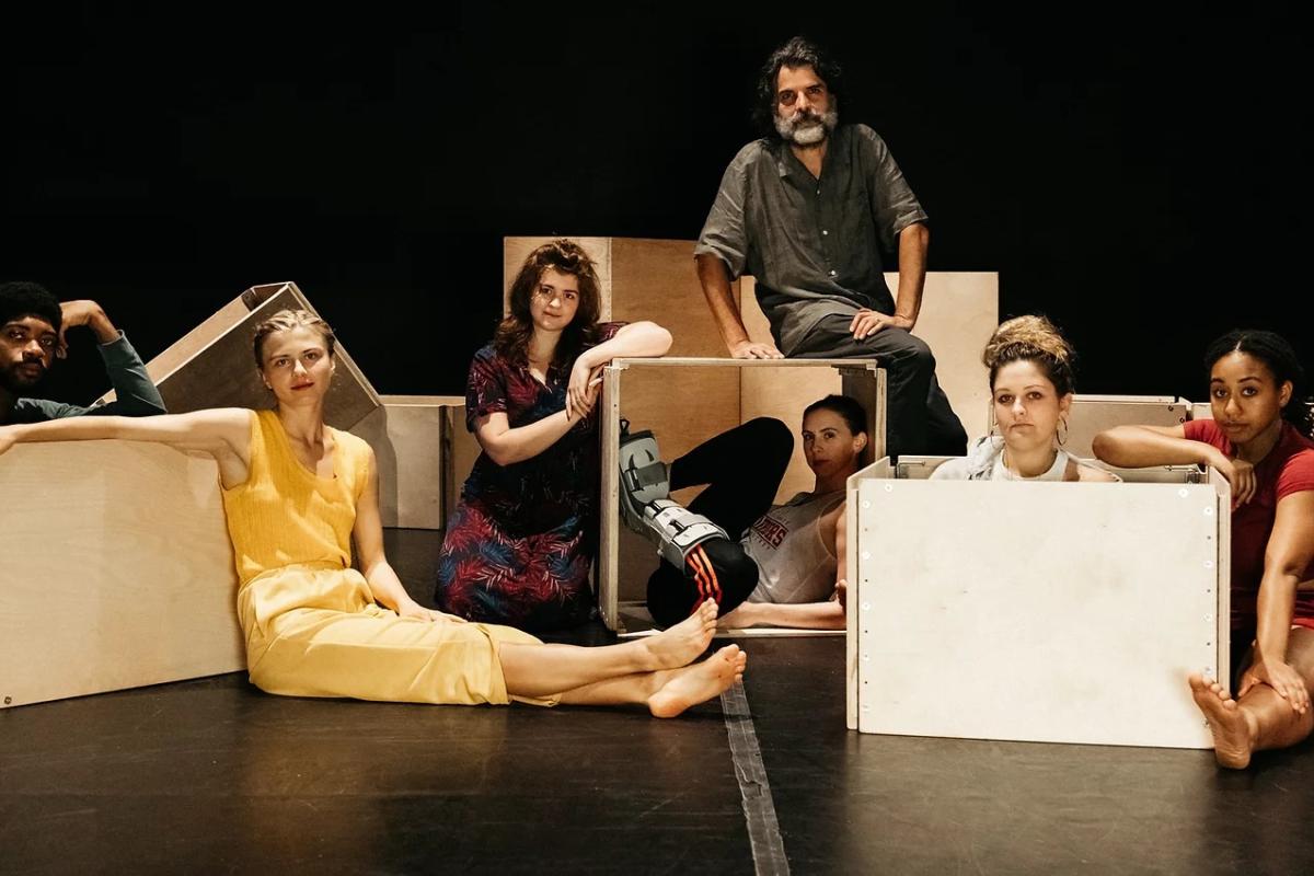 Professor of Mechanical Engineering Benjamin Linder sits among dancer-choreographer and Sketch Model partner Jenna Pollack, alongside fellow dancers and wooden box frames for performance props.