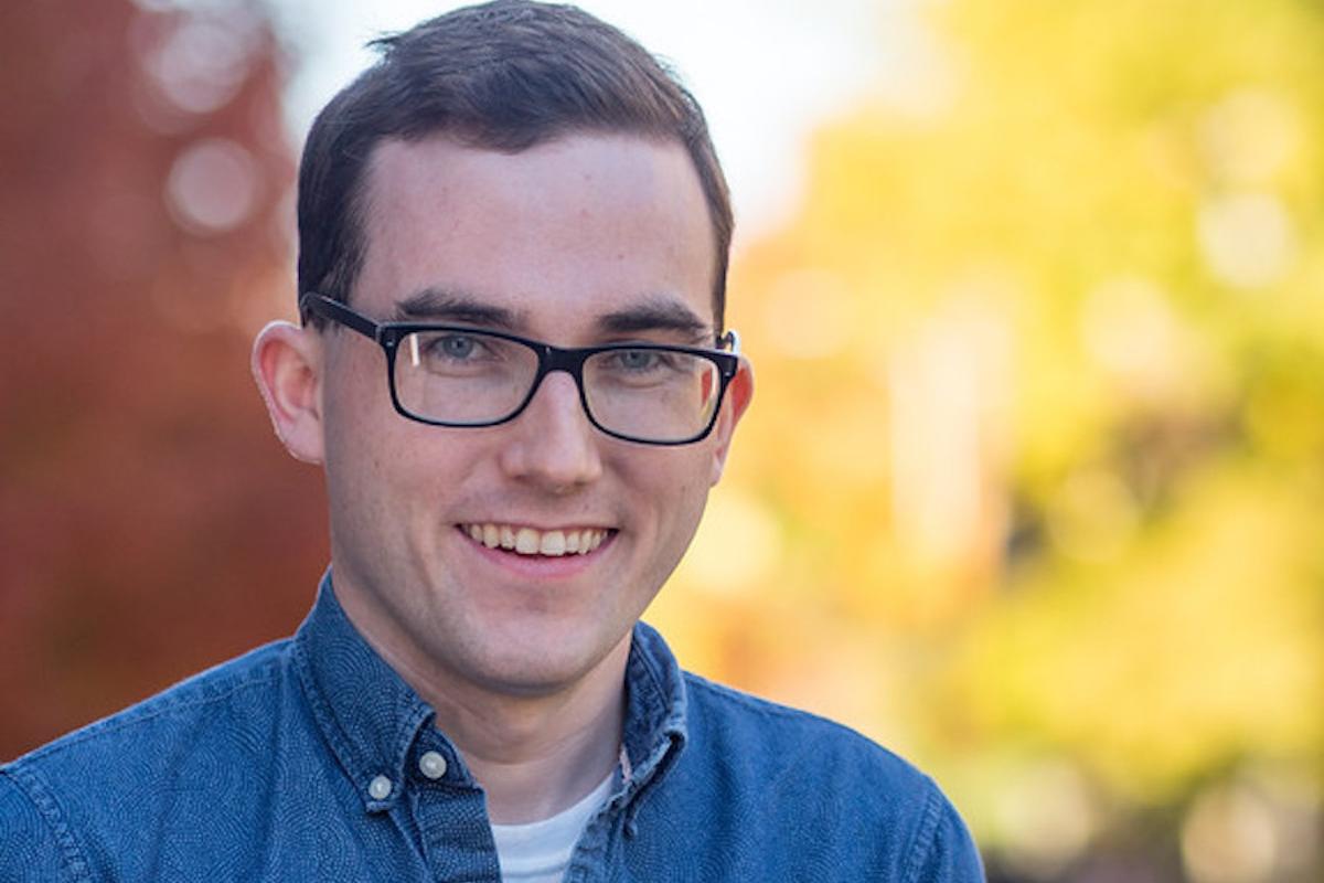 A young man smiling with glasses.