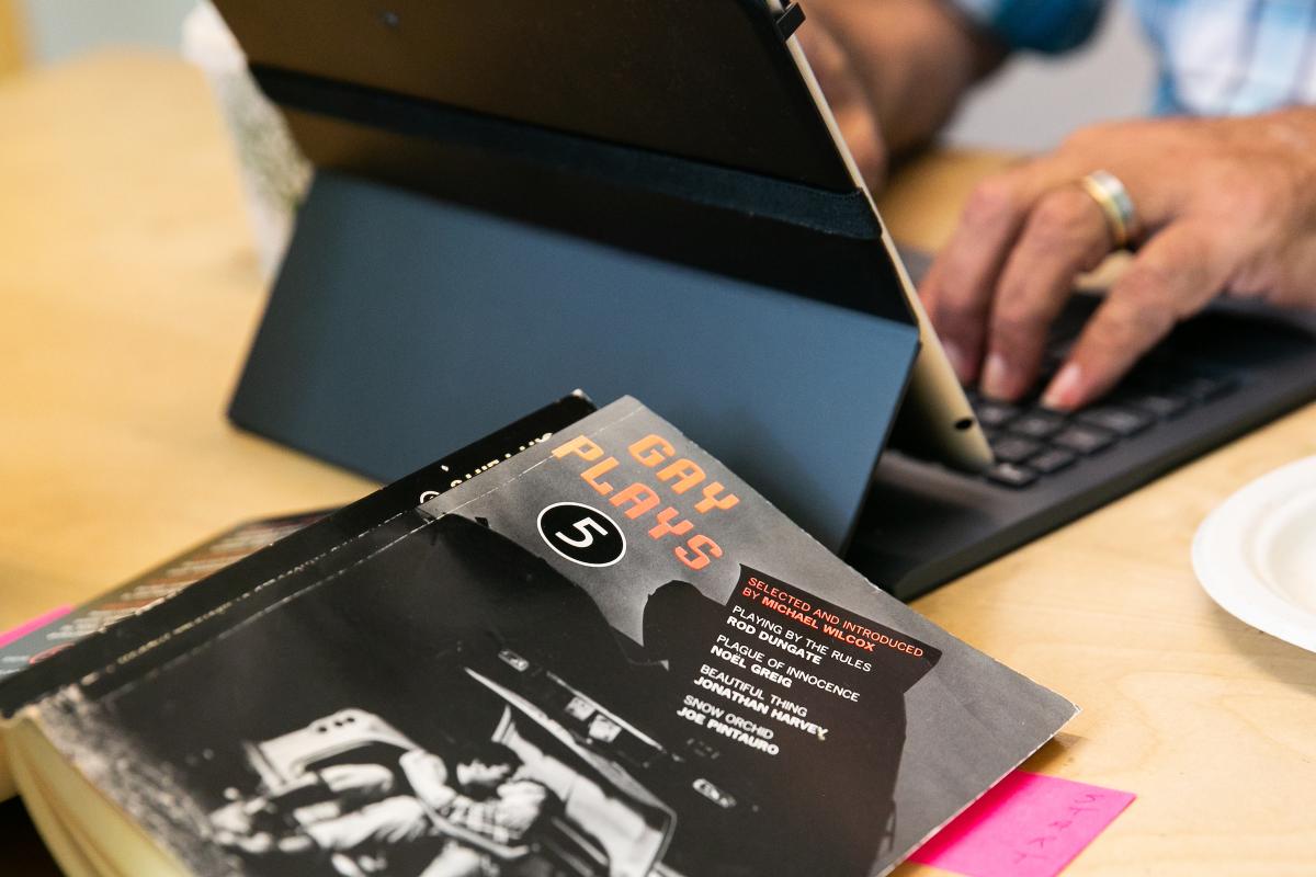 An image of a black book with someone's hands typing on a laptop in the background.