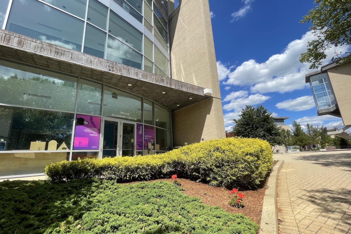 Miller Academic Center July 2022 A building is pictured with greenery and shrubs in front of it during a sunny day.
