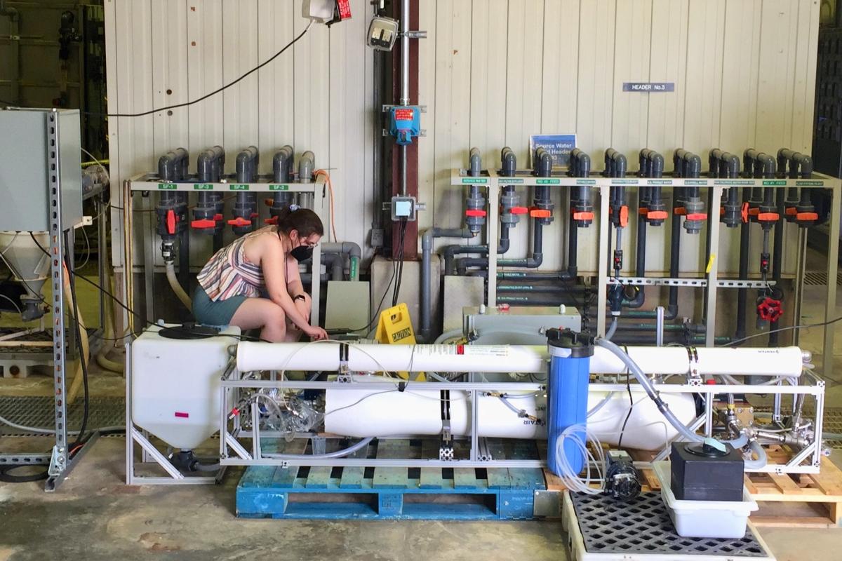 Audrey Abraham '24 is working on the purification system, with the water tanks shown on the far left and right (the tank on the left is the drinking water being produced by the team's system.)