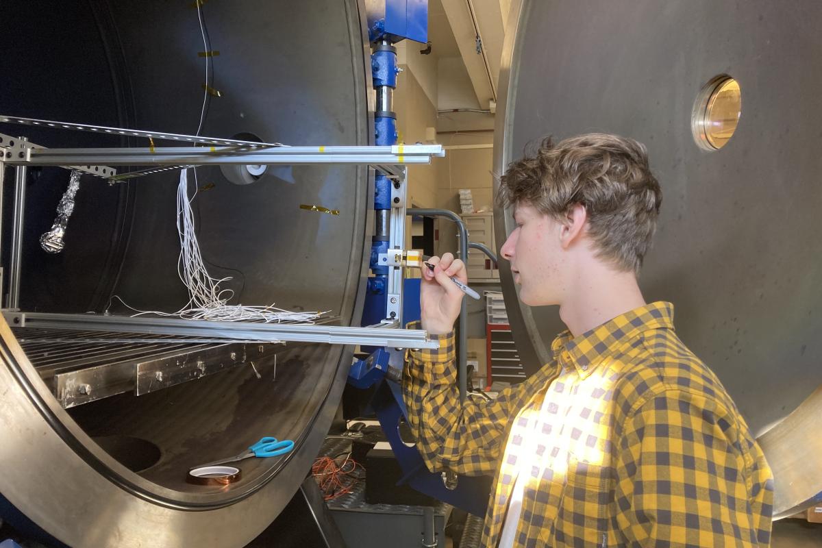 A student is pictured marking a ceramic terminal block, a component that allows electrical connections to be made to a thruster.