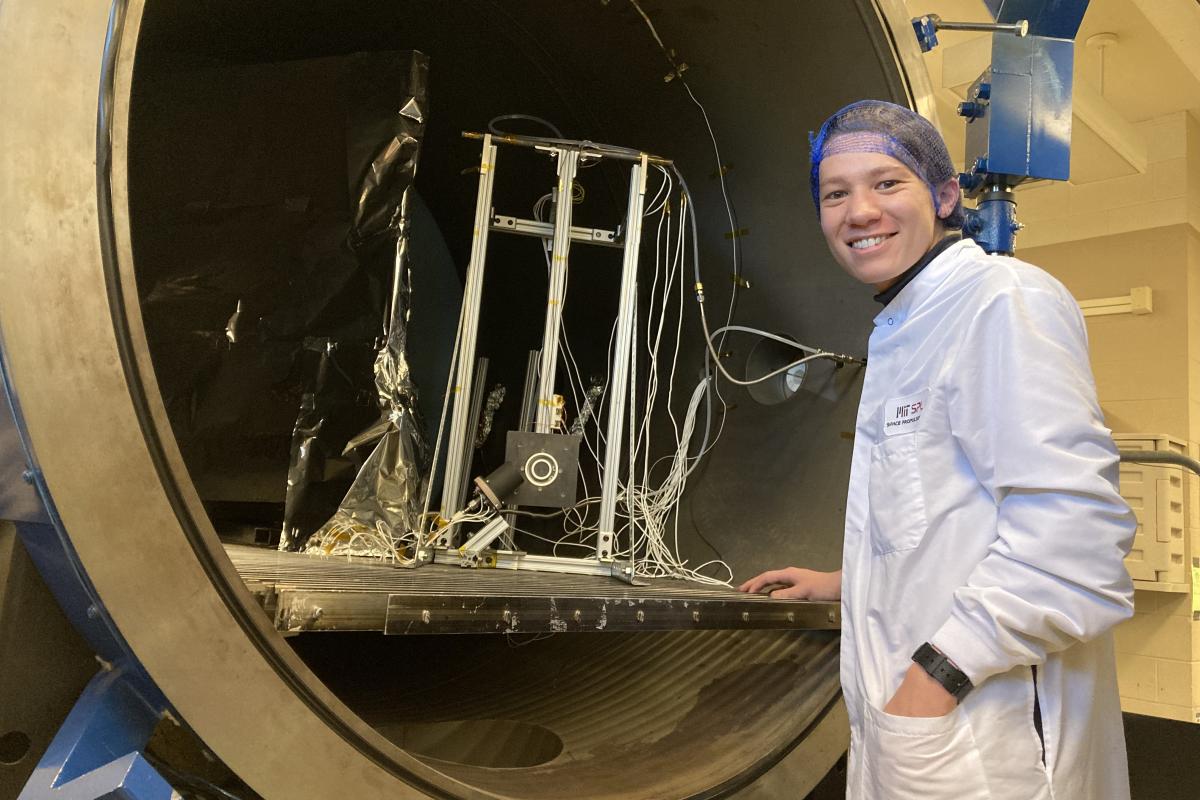 Braden Oh '23 poses with an ion thruster at MIT's Space Propulsion Lab in 2023.