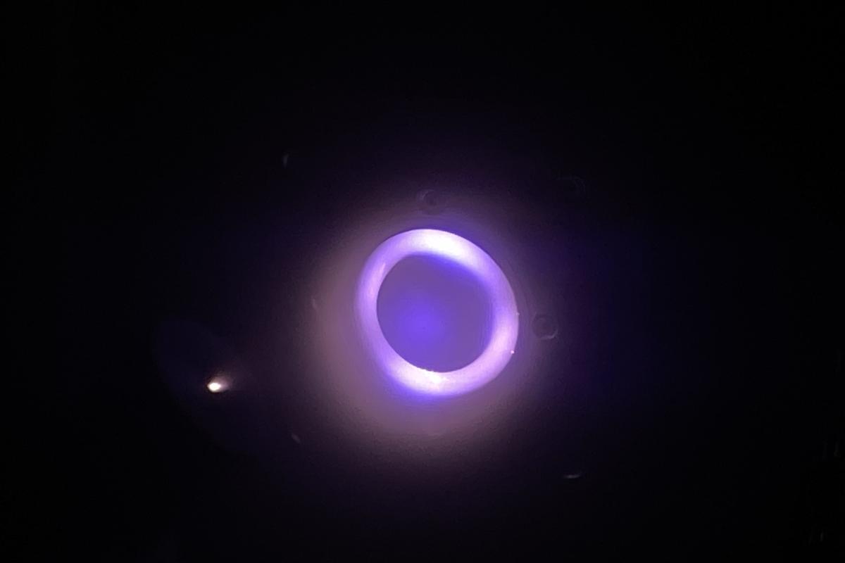 The glowing substance is a plasma ejected from the thruster.