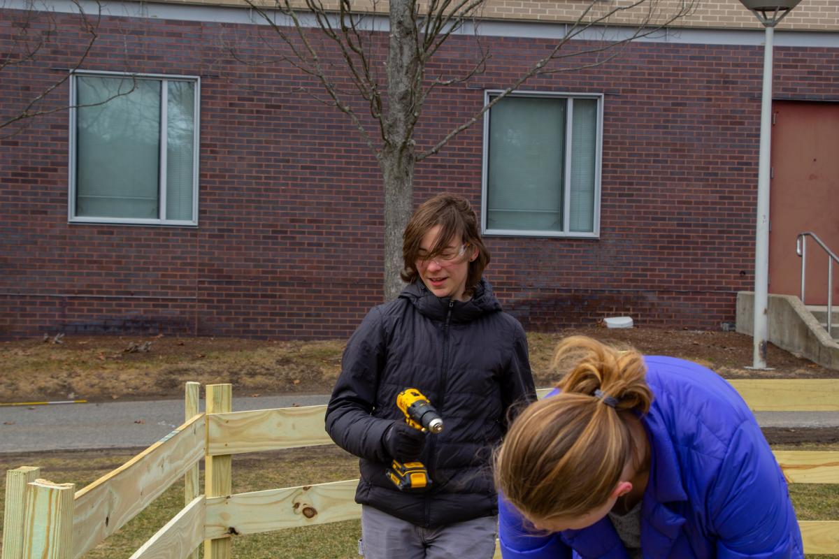 Two students - one with a cordless drill - are pictured building a Ga-Ga-Ball pit.
