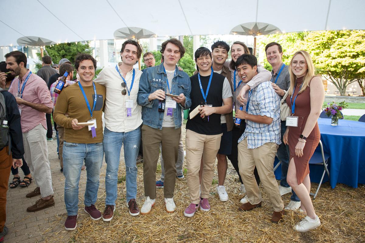 A group of Olin alumni stand together under the tent and smile.