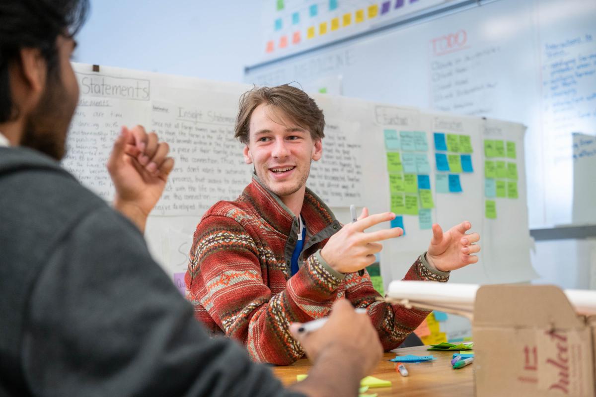 A student gestures with his hands in a classroom.