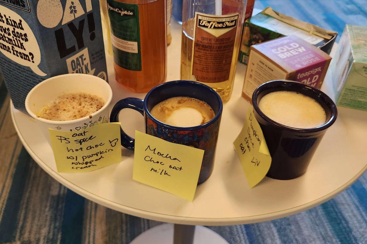 Three types of coffee drinks in mugs with syrups and oat milk on a table