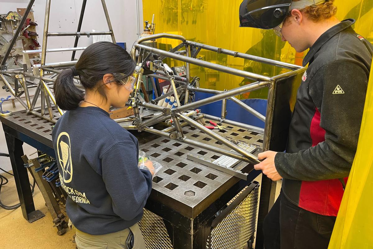 Two Olin students working in the shop building the metal framework for SAE formula chassis