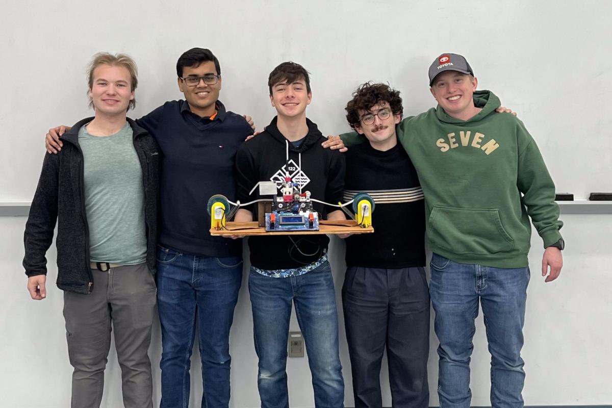 Five Olin College of Engineering students hold up a physical, electromechanical Turing Machine.