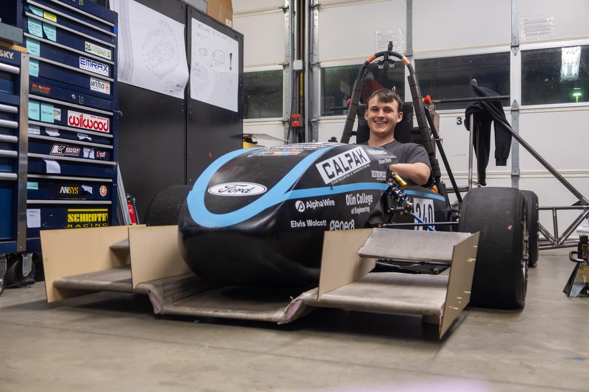 Alton Coolidge '26 seen in the driver's seat of a black with blue stripes Formula SAE vehicle, while it sits parked in a shop. Alton Coolidge '26 seen in the driver's seat of a black with blue stripes Formula SAE vehicle, while it sits parked in a shop.