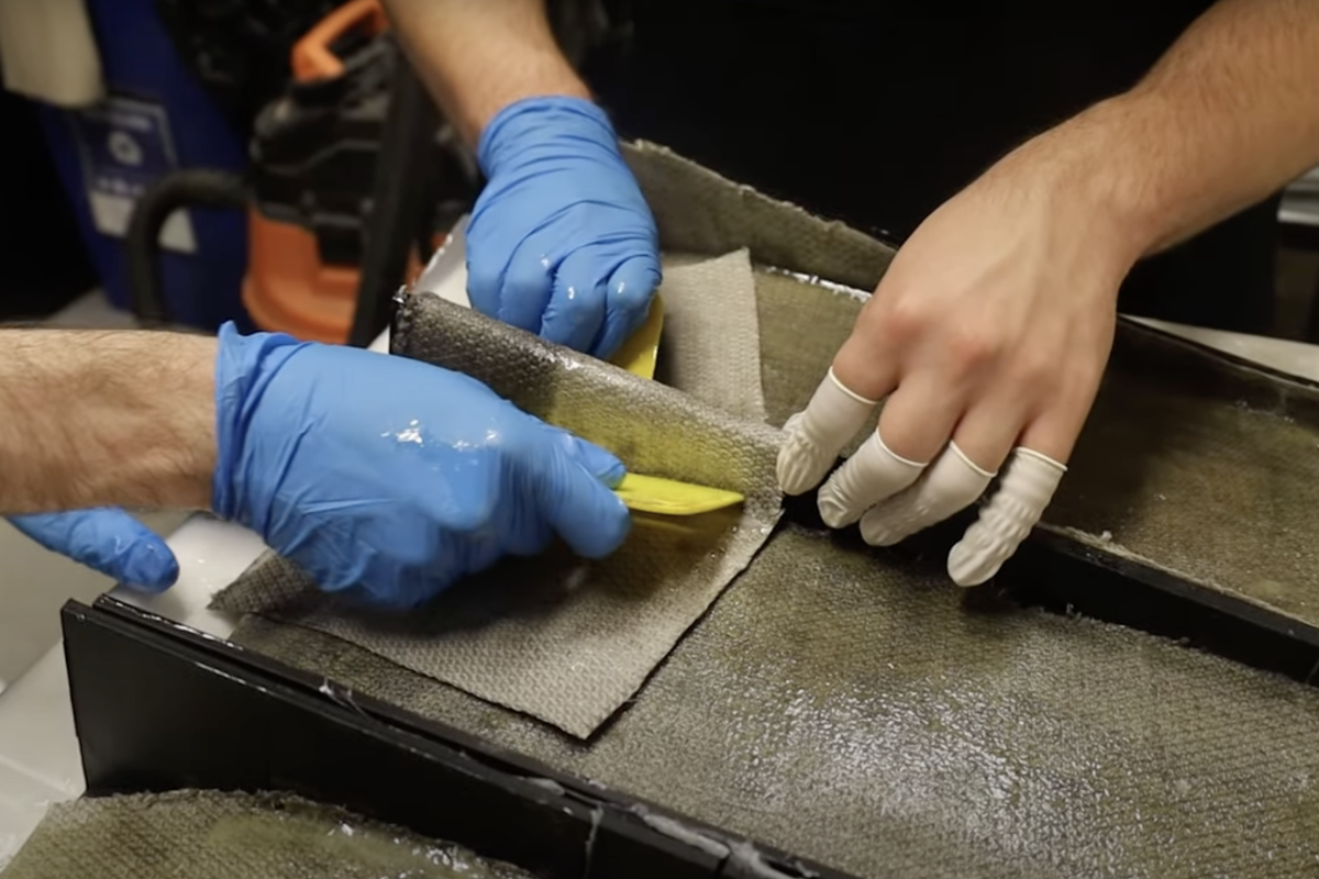 Hands shown working on a car wing putting on its first layer of hemp composite.