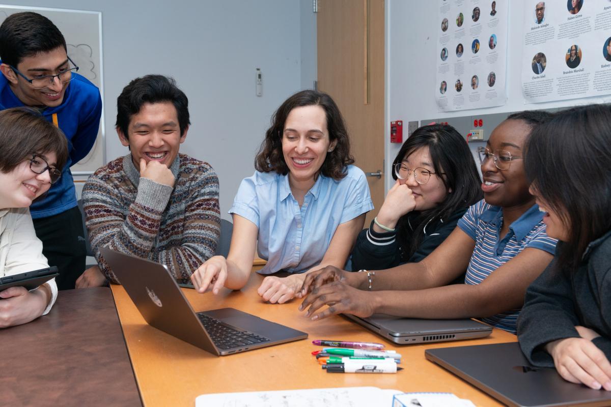 Professor Andrea Cuadra and Students Professor Andrea Cuadra gathered around a computer with her students