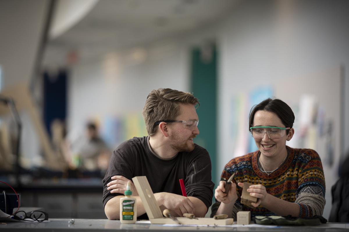 Two students working with wood in the Miller Academic Center (MAC). Two students work with wood in the Miller Academic Center (MAC).