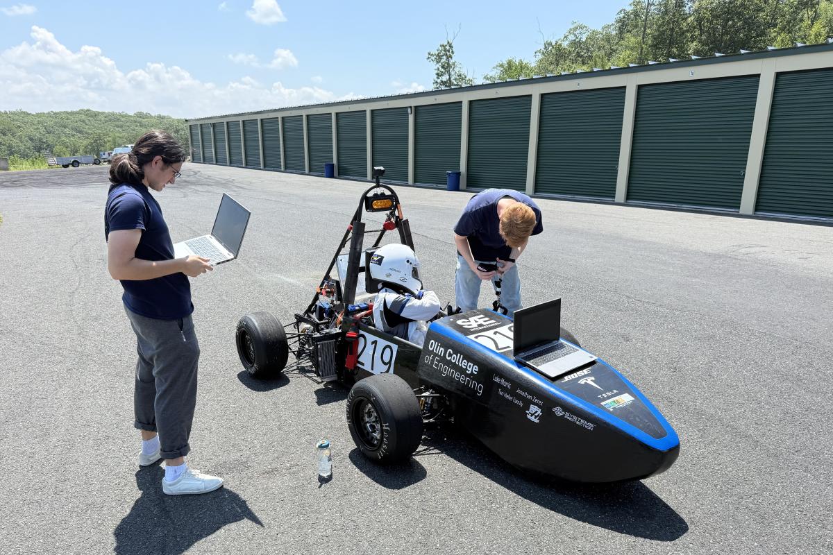 Members of the Olin Electric Motorsports Team are seen working on their race car on the track.