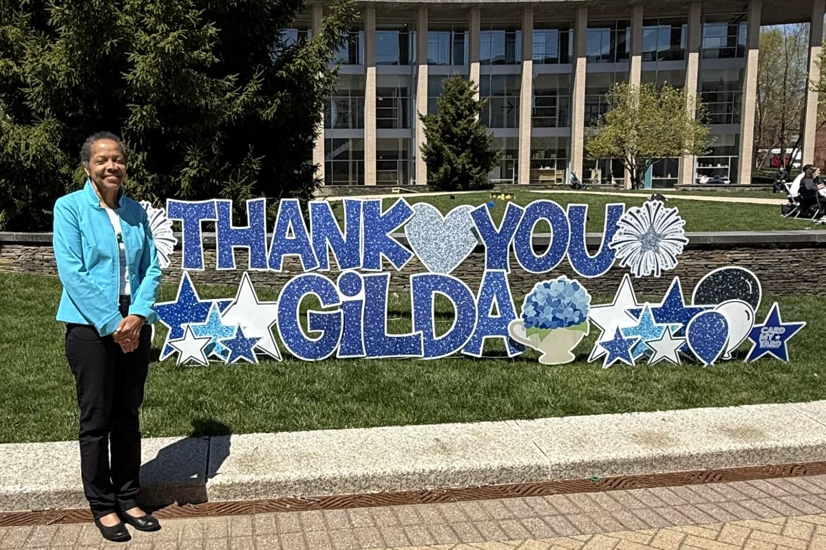 Olin College's Second President Gilda A. Barabino, Ph.D, stands in front of a "Thank you Gilda" sign.