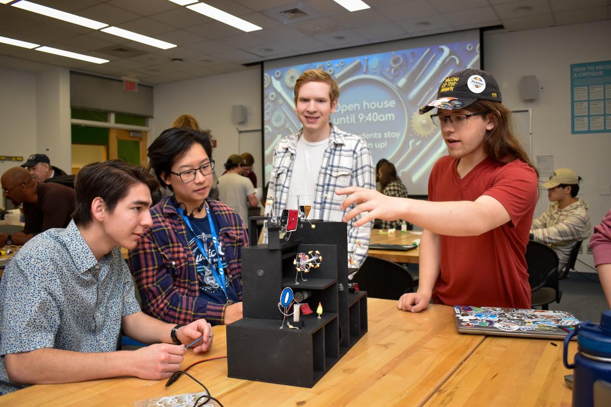 Four students gather around their final MechProto project. 
