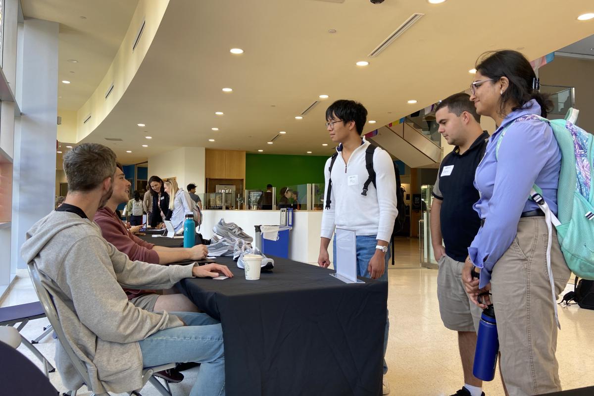 Students gather around a table with a black tablecloth.