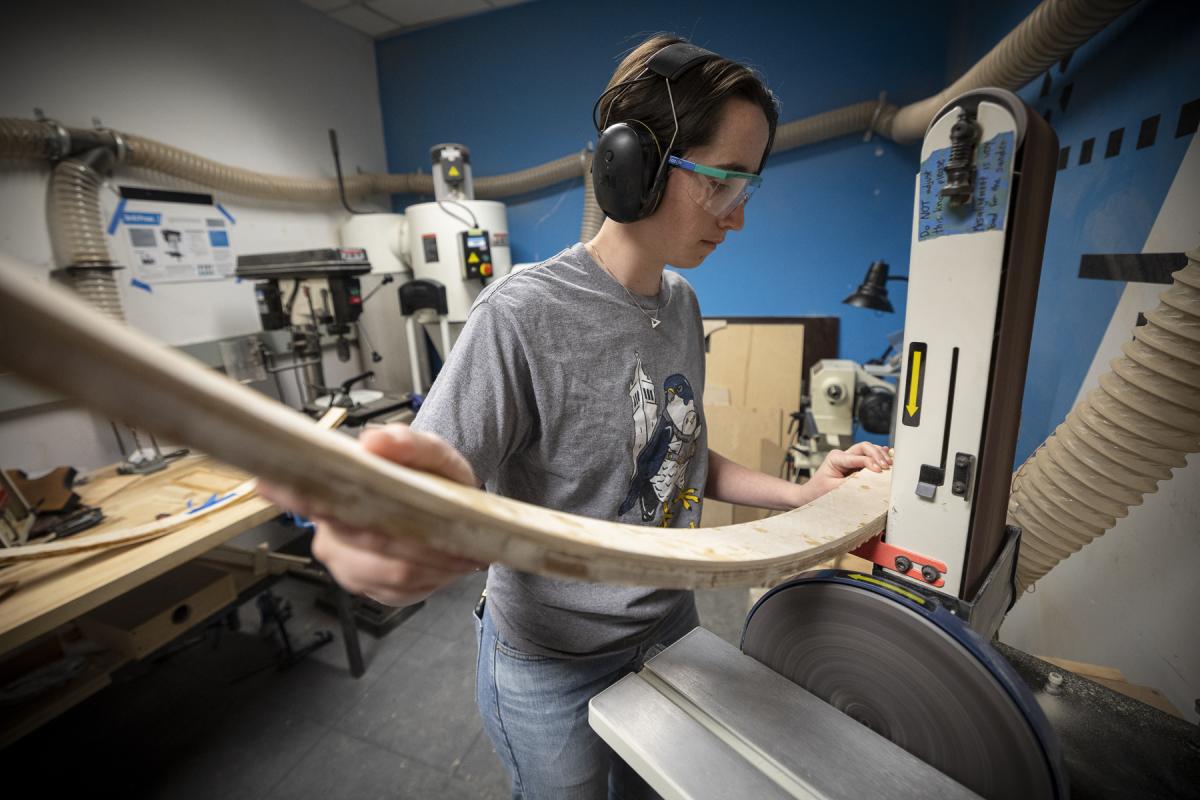 An Olin College student works with a large piece of wood in the Wood Shop in the MAC..