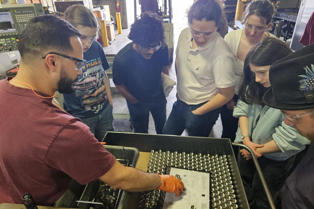 Students and a staff member stand around a man presenting information about Darco's products.