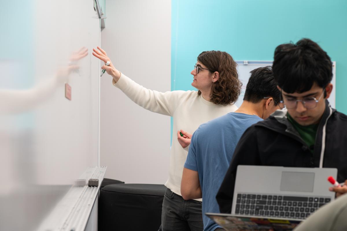 Three Probabilistic Robotics students writing on a whiteboard
