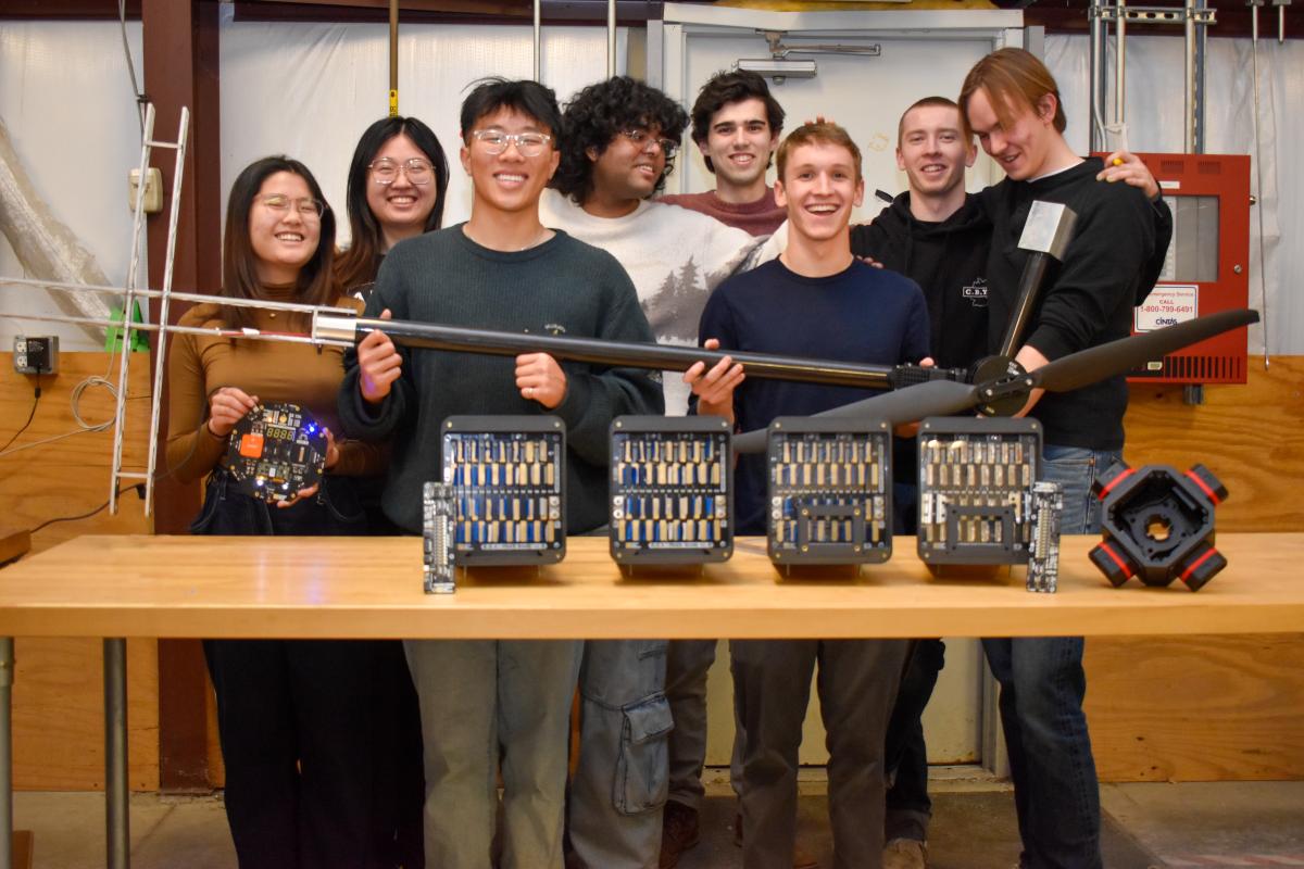 Members of the OCTAL team pose with a frame arm and propeller