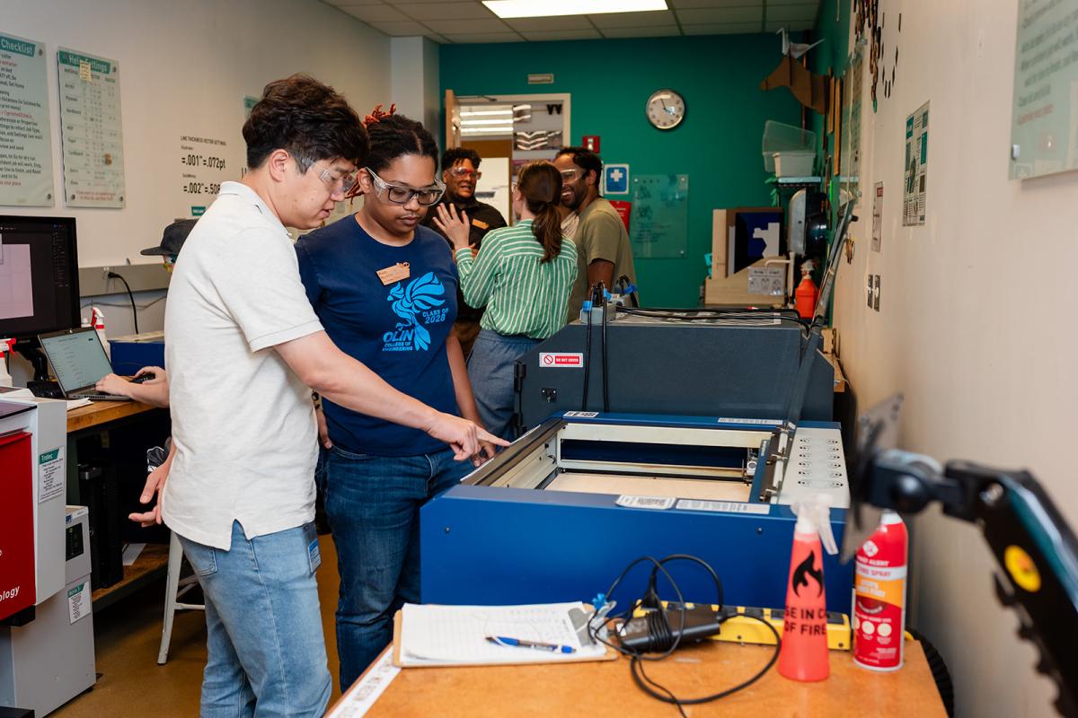 A Makerspace Institute participant learning from a student about one of the Shop's machines. 